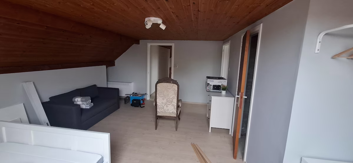 Combles aménagés avec mur en lattes de bois et plafond mansardé peint, chantier de peinture en région liégeoise
